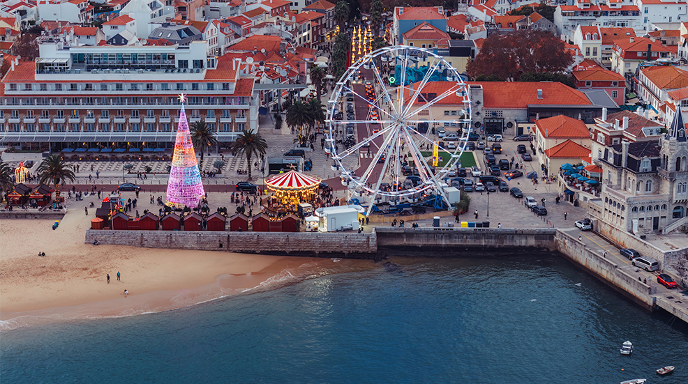 Aerial drone view of Cascais, Portugal with the giant ferris wheel set up for the Christmas season near the beach